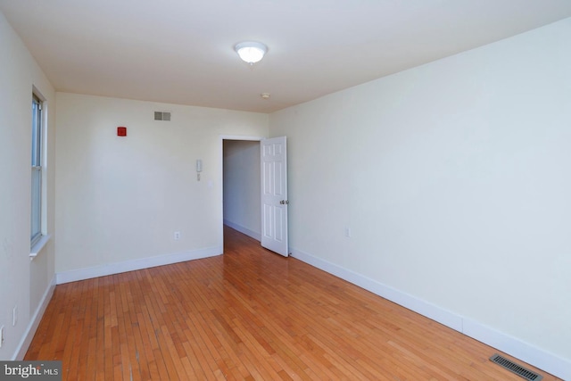 spare room featuring light wood-type flooring, visible vents, and baseboards