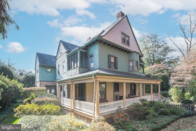 view of home's exterior featuring covered porch, roof with shingles, and a chimney