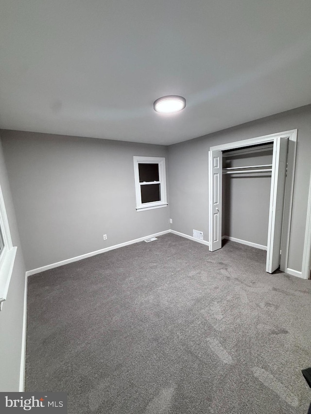 unfurnished bedroom with carpet flooring, visible vents, baseboards, and a closet