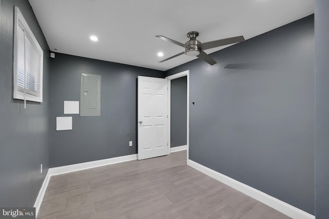 empty room with electric panel, baseboards, ceiling fan, light wood-style floors, and recessed lighting