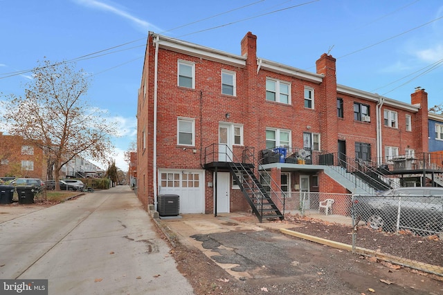 exterior space featuring an attached garage, central AC, fence, driveway, and stairway