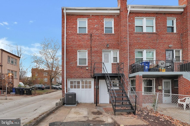 view of front of house featuring brick siding, driveway, fence, and central air condition unit