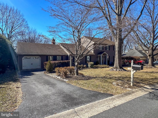 view of front of house with aphalt driveway, a chimney, and an attached garage