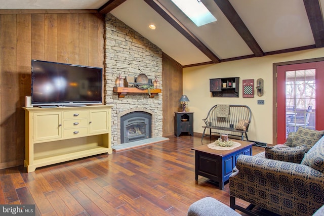 living area featuring lofted ceiling with skylight, a fireplace, baseboards, and wood finished floors