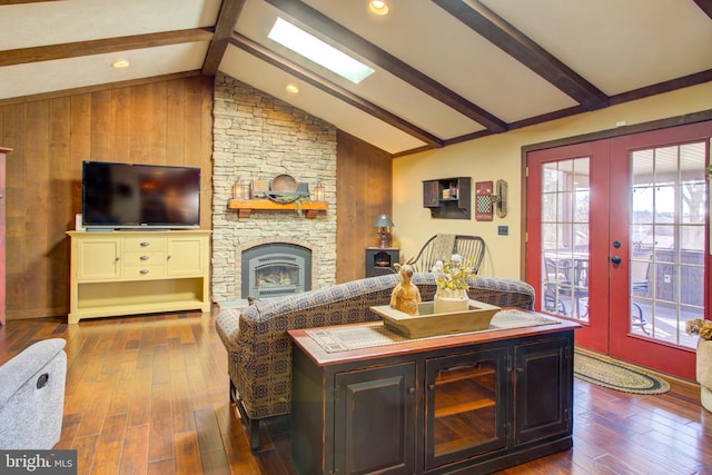 living room with lofted ceiling with beams, a stone fireplace, french doors, and dark wood-style flooring