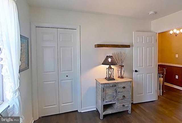 corridor with baseboards, a chandelier, and dark wood-style flooring