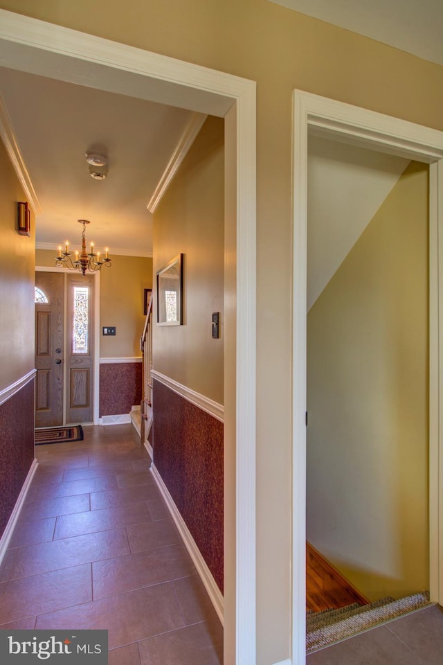 entryway with a wainscoted wall, ornamental molding, stairway, and an inviting chandelier