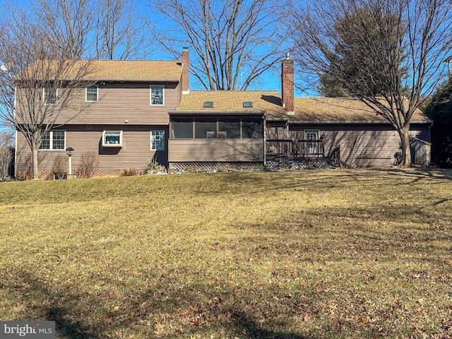 rear view of property with a sunroom, a lawn, and a chimney