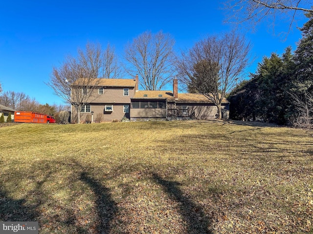 back of house featuring a chimney and a lawn