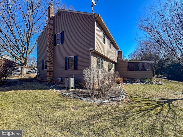 view of side of home featuring a lawn, central AC, a chimney, and a sunroom