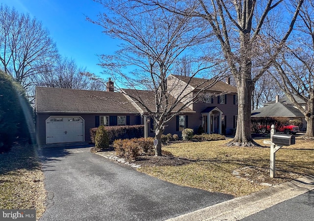 view of front of property with a garage, driveway, a chimney, and roof with shingles