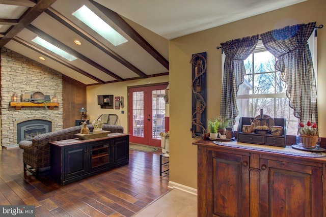 kitchen featuring vaulted ceiling with skylight, open floor plan, wood finished floors, french doors, and a fireplace