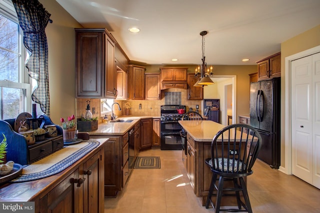 kitchen with a wealth of natural light, decorative backsplash, a kitchen island, black appliances, and a sink