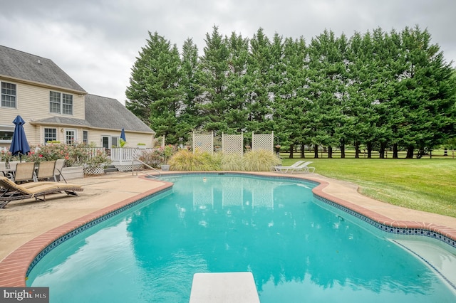 outdoor pool with a diving board, a patio, a lawn, and fence