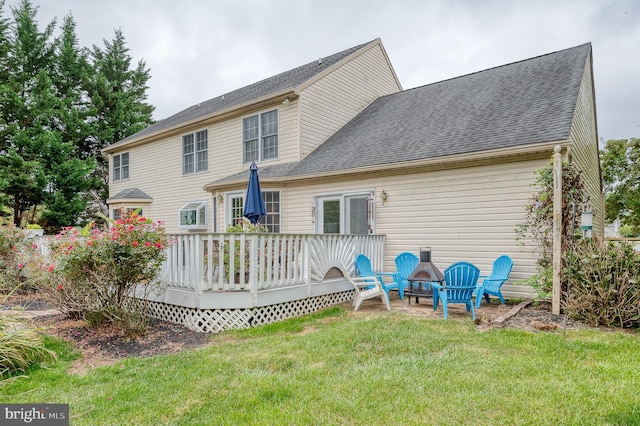 rear view of property featuring a deck, a shingled roof, and a lawn