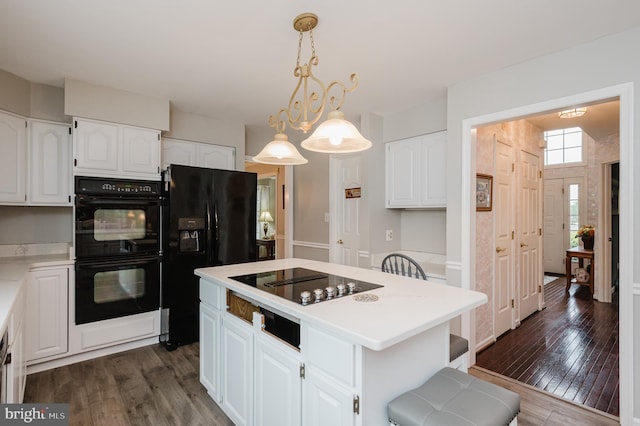 kitchen with dark wood-style floors, light countertops, white cabinets, a kitchen island, and black appliances