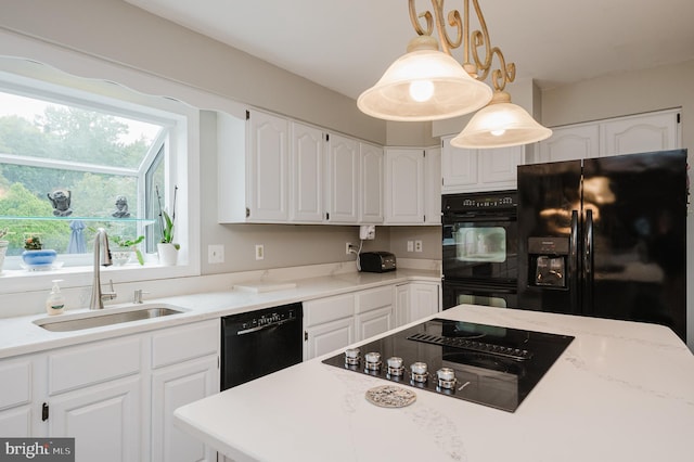 kitchen featuring a sink, white cabinets, light countertops, black appliances, and decorative light fixtures