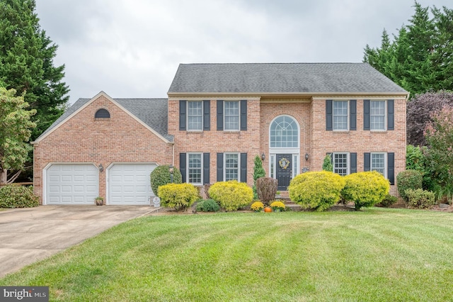 view of front facade featuring a garage, driveway, roof with shingles, a front yard, and brick siding