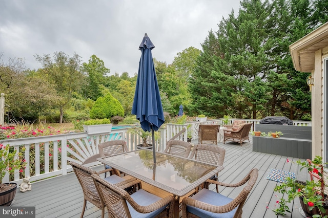 wooden deck with an outdoor pool and outdoor dining space