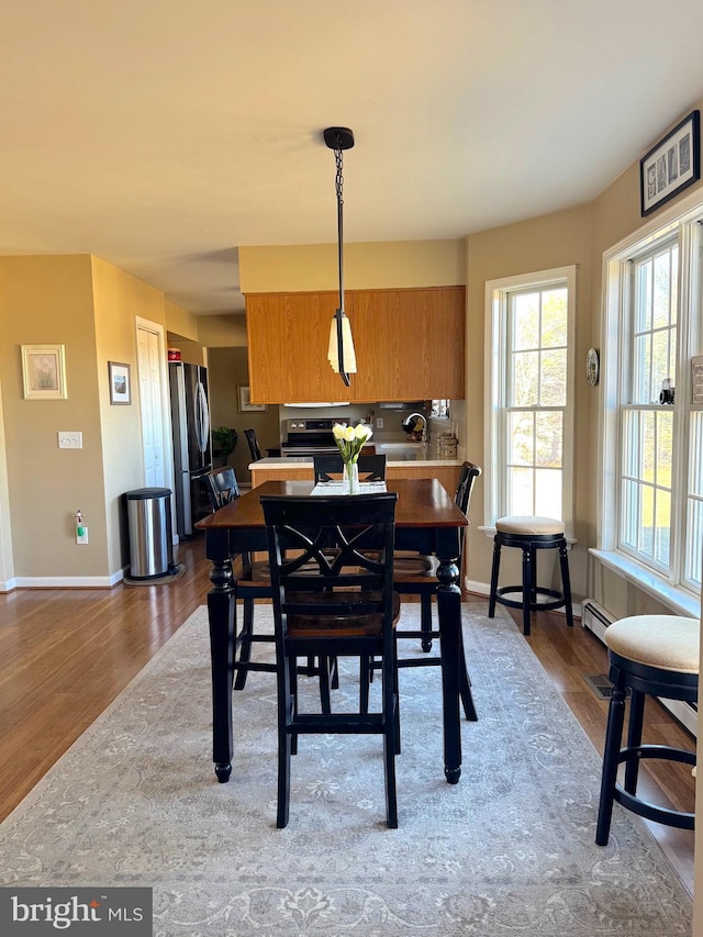 dining room featuring a baseboard radiator, baseboards, and wood finished floors