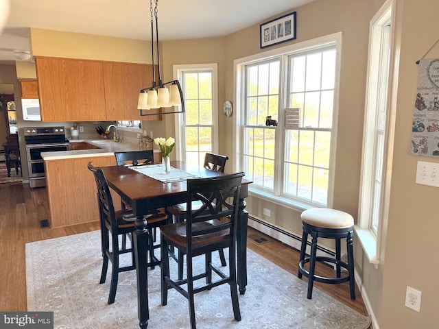 dining space with light wood-type flooring, visible vents, and baseboards