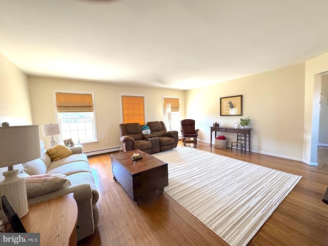 living room featuring a baseboard heating unit, baseboards, and wood finished floors