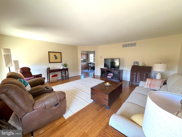 living area with visible vents and wood finished floors