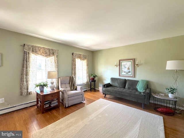 sitting room with a baseboard heating unit, baseboards, and wood finished floors