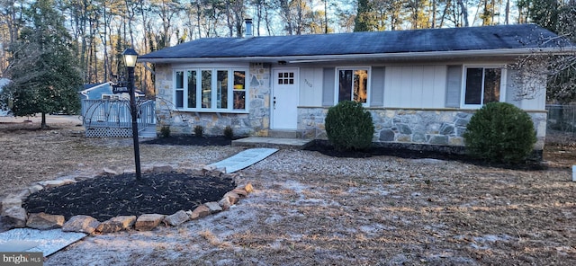 view of front facade featuring stone siding and a wooden deck