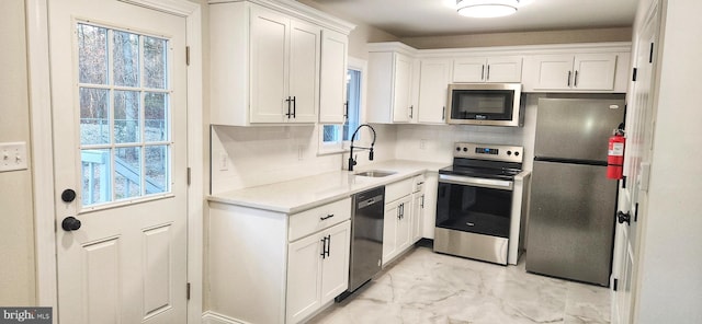 kitchen with marble finish floor, stainless steel appliances, light countertops, white cabinets, and a sink