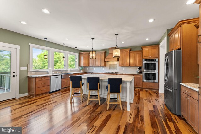 36976 Walnut Park Ln, Purcellville, VA 20132 - kitchen featuring appliances with stainless steel finishes, premium range hood, brown cabinetry, a center island, and recessed lighting