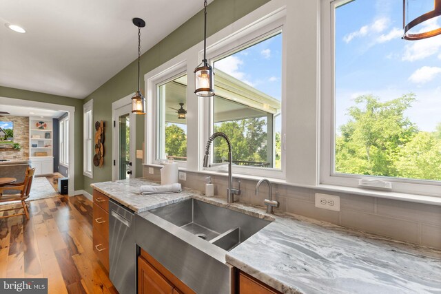 36976 Walnut Park Ln, Purcellville, VA 20132 - kitchen with wood finished floors, a sink, brown cabinetry, dishwasher, and light stone counters