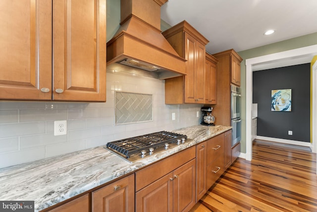 36976 Walnut Park Ln, Purcellville, VA 20132 - kitchen with custom exhaust hood, appliances with stainless steel finishes, wood finished floors, light stone countertops, and brown cabinets