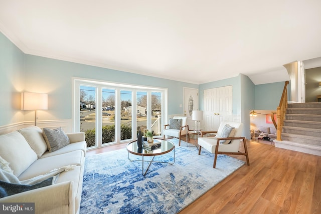 living area with stairway, wood finished floors, and ornamental molding