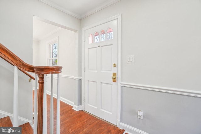 foyer entrance with ornamental molding, stairway, baseboards, and wood finished floors