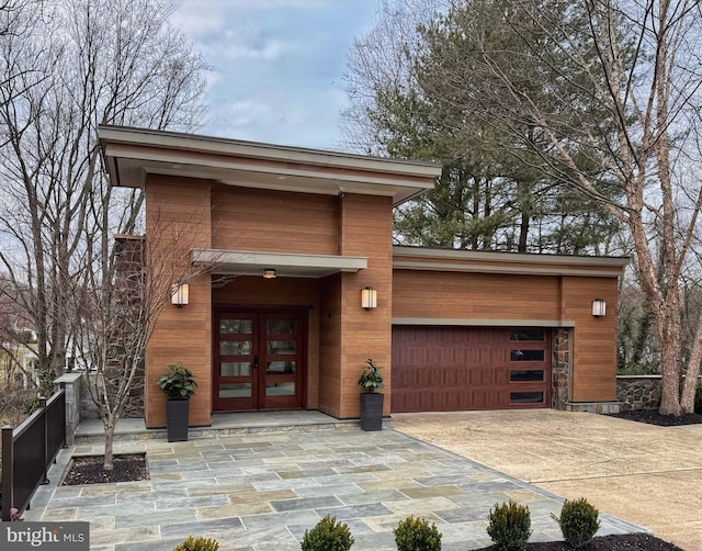 view of exterior entry featuring french doors, a garage, and driveway