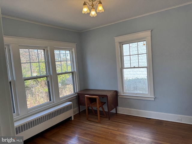 unfurnished room with dark wood finished floors, radiator, an inviting chandelier, ornamental molding, and baseboards