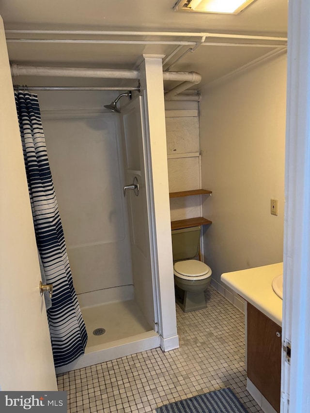 bathroom featuring toilet, a stall shower, tile patterned flooring, and vanity