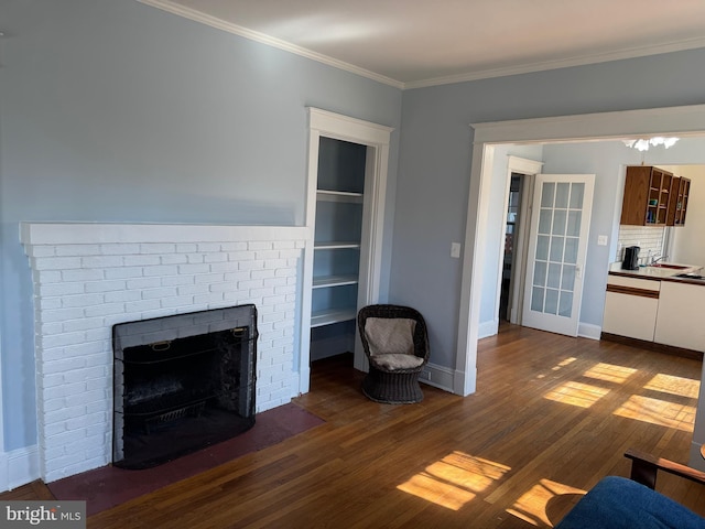 unfurnished living room with dark wood-style floors, a brick fireplace, crown molding, and baseboards