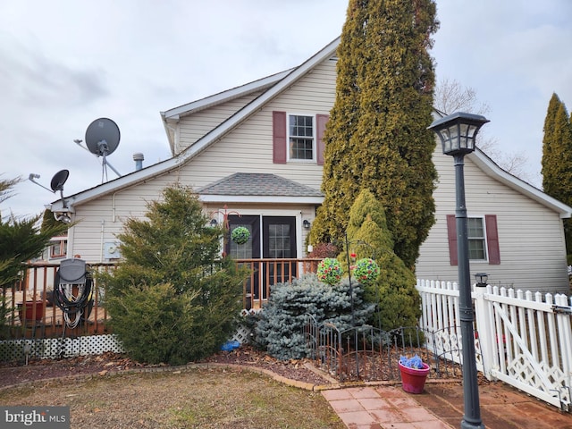 view of front of house featuring roof with shingles, fence, and a wooden deck