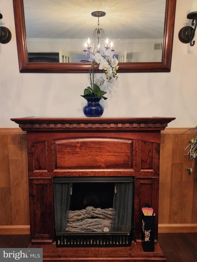 room details featuring ornamental molding, a fireplace, visible vents, and an inviting chandelier