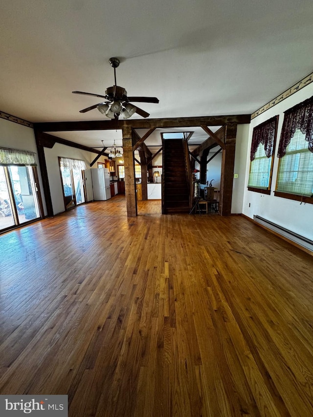 unfurnished living room featuring a baseboard radiator, ceiling fan with notable chandelier, wood finished floors, and a healthy amount of sunlight