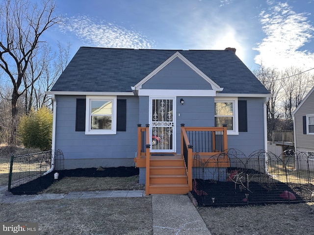 bungalow-style house with roof with shingles, a chimney, and fence