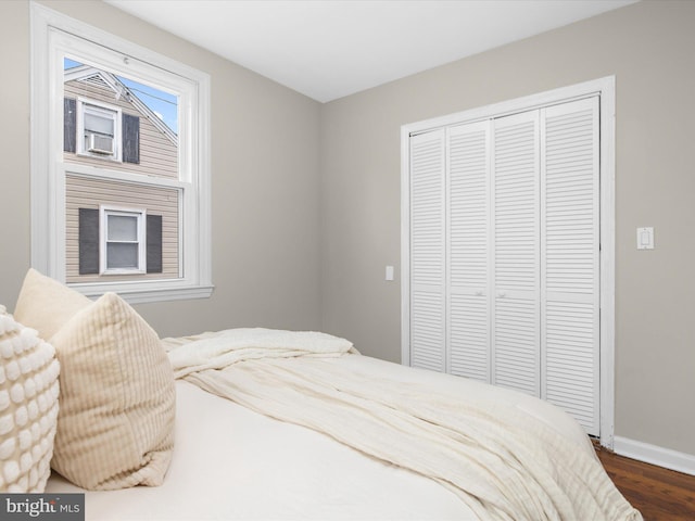 bedroom with baseboards, dark wood-style flooring, and a closet