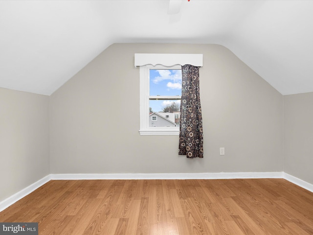 bonus room featuring baseboards, vaulted ceiling, and light wood finished floors