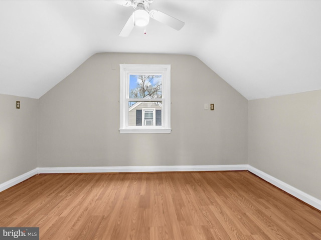 additional living space featuring light wood-type flooring, vaulted ceiling, baseboards, and ceiling fan