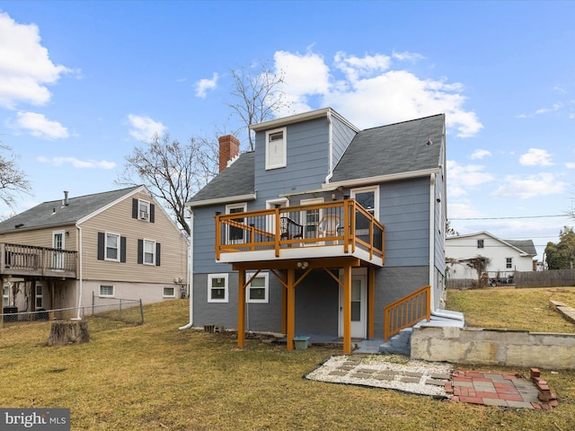 back of house featuring a deck, a chimney, fence private yard, and a lawn