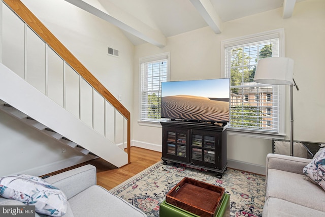 living room with baseboards, visible vents, lofted ceiling with beams, wood finished floors, and stairs