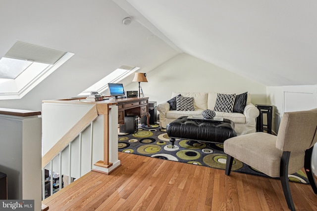 living area with lofted ceiling with skylight and wood finished floors