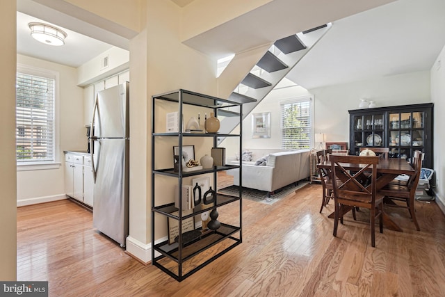 dining space featuring light wood finished floors, plenty of natural light, and baseboards